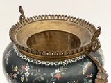 a black vase with a gold handle and a flower design on it