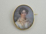 an antique portrait of a woman in a white dress is shown in a gold plated pin