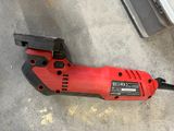 a red and black electric tool on the ground