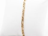 un bracelet en chaîne d'or posé sur un coussin blanc