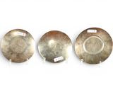 three silver plates with labels on them sitting on a white surface