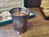 a silver cup and a spoon on a wooden table