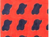 a red and blue rug with black spots on it