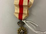 une image représentant une médaille d'or entourée d'un ruban rouge et blanc