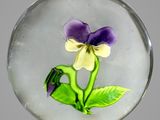 un presse-papier en verre contenant une fleur violette