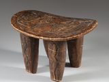 an old wooden stool with carved legs on a grey background