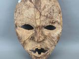 gros plan d'un masque en bois sur une surface blanche