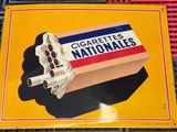 une enseigne indiquant « Cigarettes Nationales » sur la façade d'un immeuble