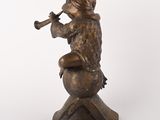 statue of a boy sitting on a ball playing a trumpet