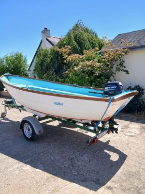 un petit bateau sur une remorque garé devant une maison