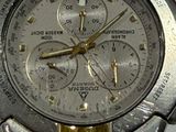 a silver and gold watch on display on a white surface