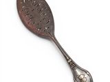 an antique spoon with a leaf design on it on a white surface