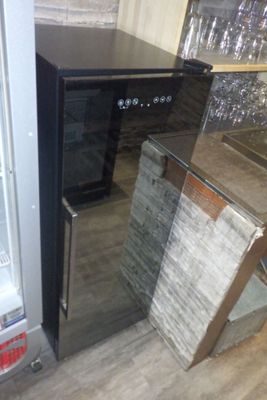 une photo d'un réfrigérateur dans un magasin, avec des verres à vin sur les étagères