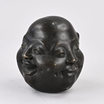 une sculpture noire représentant un visage sur une surface blanche