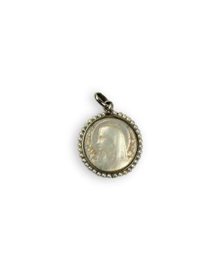 a close up of a coin in a pendant on a white background