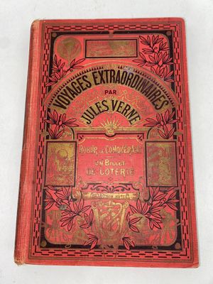 un vieux livre rouge orné de lettres dorées, posé sur une surface blanche