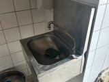 un lavabo dans un coin de la salle de bains, avec un seau d'eau