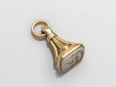 une image représentant un pendentif en forme de clochette dorée sur un fond blanc