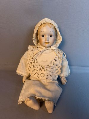 une petite poupée assise sur une surface bleue