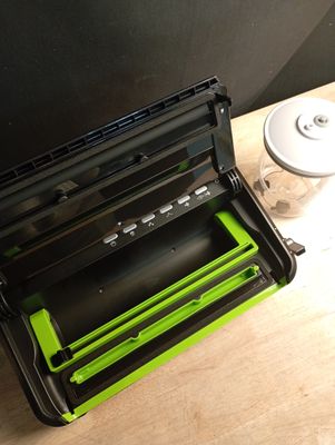 un appareil noir et vert posé sur une table à côté d'une tasse de café