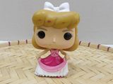 disney princess figurine with pink dress and white bow sitting on a basket