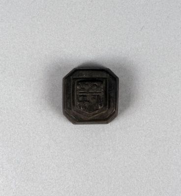 a small black metal object with a crest on it