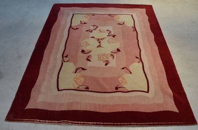 un tapis posé à même le sol, bordé d'une frange rouge