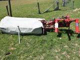 a tractor that is sitting in the grass with a tarp on it