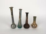 quatre vases en verre de couleurs différentes posés les uns à côté des autres sur une surface blanche