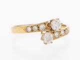 a close up of a gold ring with two diamonds on it