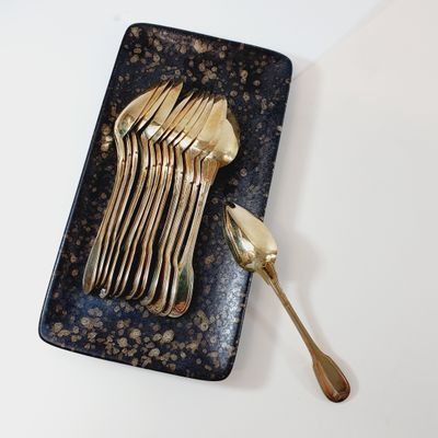 a black plate with gold forks and spoons on it