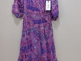 a purple dress hanging on a hanger against a wall