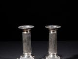 a pair of silver candlesticks on a black background