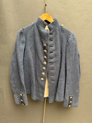 une vieille veste bleue accrochée au mur à côté d'un cintre en bois