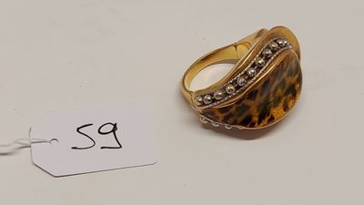 gros plan d'une bague sur une surface blanche avec une étiquette de prix