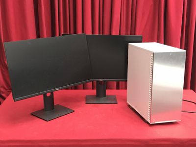 deux écrans d'ordinateur posés sur une table rouge, devant un rideau rouge