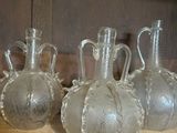 quatre vases en verre transparent posés sur une étagère en bois dans une pièce