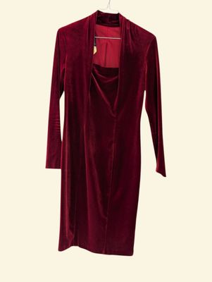 the red velvet dress is hanging on a hanger on a white wall