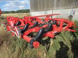 a couple of red farm implements sitting on top of a lush green field