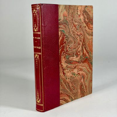 an old book with a red cover sitting on top of a white table