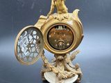 a gold clock sitting on a table next to a gold coin