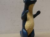 une petite figurine de dinosaure bleue et jaune posée sur une table