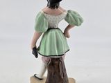 a figurine of a woman in a green dress and hat