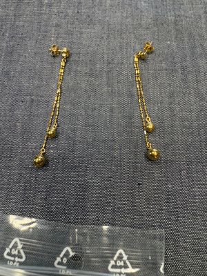 un gros plan sur une paire de boucles d'oreilles en or posées sur une table