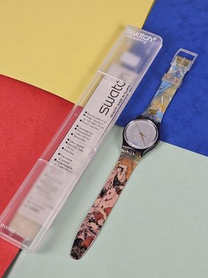 a watch sitting on a colorful surface next to a pen