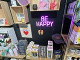 a display of various items in a store with a neon sign that says be happy