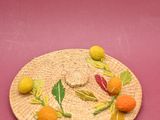a straw hat with oranges and green leaves on it