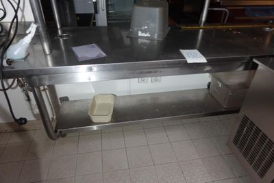 une table en acier inoxydable sur laquelle est posée une poubelle
