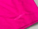 un gros plan d'une serviette rose posée sur une surface blanche