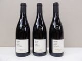 trois bouteilles de vin sont alignées sur une table